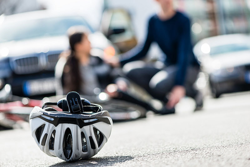 Bicyclist helmet lays on the road in the foreground as an injured person is attended to by automobile driver in Lehigh Valley.