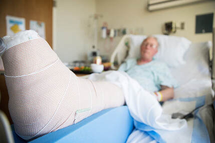 Man in hospital bed with leg propped up in a cast from an auto accident in Lehigh Valley.